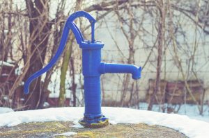 Unlike this old fashion hand water pump, follow these easy steps to winterize your outdoor faucets from winter's icy grip.